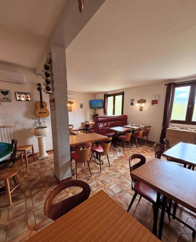 a restaurant with tables and chairs and a guitar on the wall at Hôtel - Pub Le Petit Bosquet in Santo-Pietro-di-Venaco