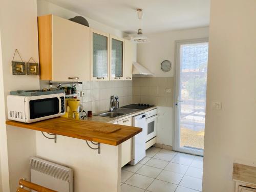 une petite cuisine avec un micro-ondes et un évier dans l'établissement Charmante maison plage, à Contis-les-Bains