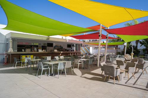 a patio with tables and chairs under colorful umbrellas at Nicholas Color Hotel in Ayia Napa