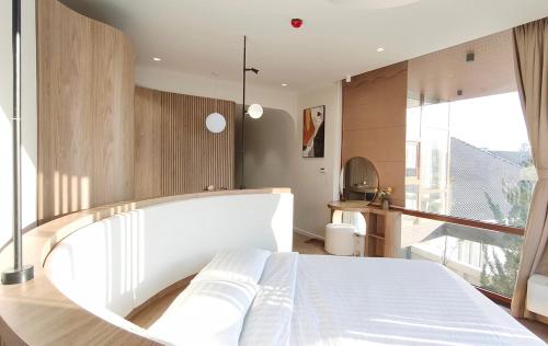 a bedroom with a white bed and a large window at Meraki Villa Đà Lạt in Khu Chi Lăng