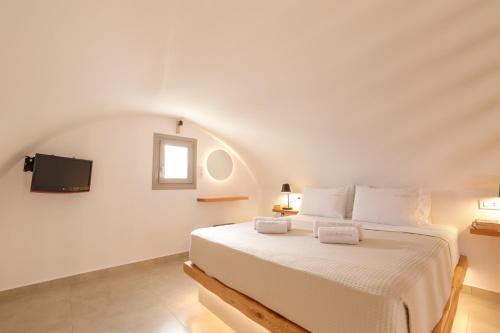 a bedroom with a white bed and a tv at Villa Eleftheria in Perivolos