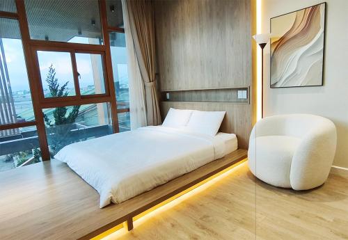 a bedroom with a white bed and a chair at Meraki Villa Đà Lạt in Khu Chi Lăng
