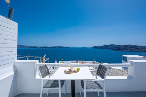 a white table and chairs on a balcony overlooking the water at Diamond Luxury Suites Collection in Oia