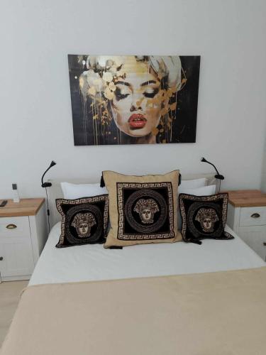a bed with four pillows and a painting on the wall at Черно море, Кранево, студио 2 in Kranevo