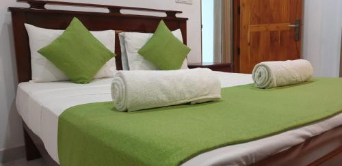 a bed with green and white pillows on it at Enara Luxury Stay in Katugastota
