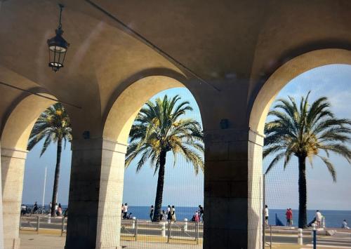 une arche avec des palmiers et l'océan en arrière-plan dans l'établissement A Studio at Nice Beach, à Nice