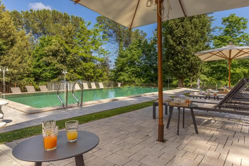 a swimming pool with two tables and an umbrella at Tenuta Villa Febea in Chiusi