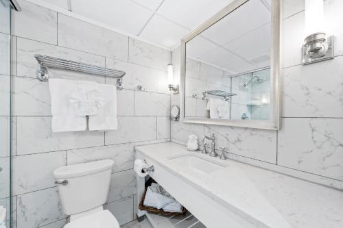 a white bathroom with a toilet and a sink at ICONA Avalon in Avalon