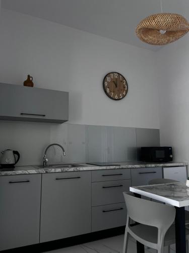 a kitchen with white cabinets and a clock on the wall at Apartamenty Róża Wiatrów in Solec-Zdrój