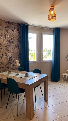 une salle à manger avec une table en bois et des rideaux bleus dans l'établissement Appartement proche Disney et Paris, à Saint-Thibault-des-Vignes