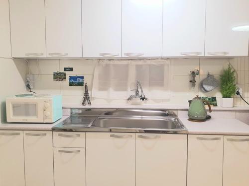 a kitchen with white cabinets and a sink and a microwave at Soo Stay in Daegu