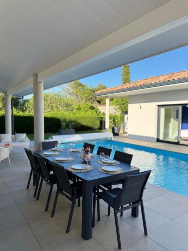 - une table à manger et des chaises sur une terrasse avec piscine dans l'établissement Villa haut de gamme Montauban, à Montauban