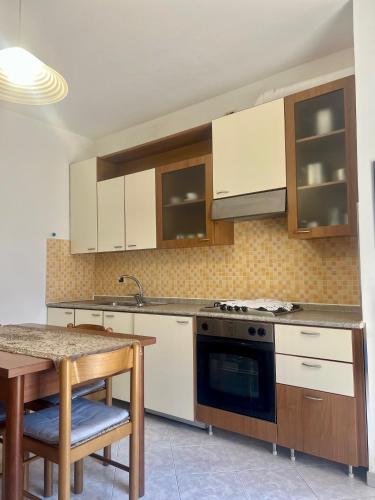 a kitchen with white cabinets and a sink and a table at Hotel Villa Luigia in Rimini