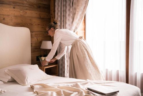 a woman in a wedding dress standing next to a bed at Auberge de La Maison in Courmayeur