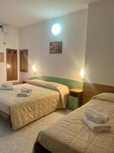 two beds in a hotel room with towels on them at Hotel Villa Luigia in Rimini