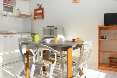 une cuisine avec une table avec des chaises et un micro-ondes dans l'établissement Marelia by POM, pkg, logia, au Cap d'Agde