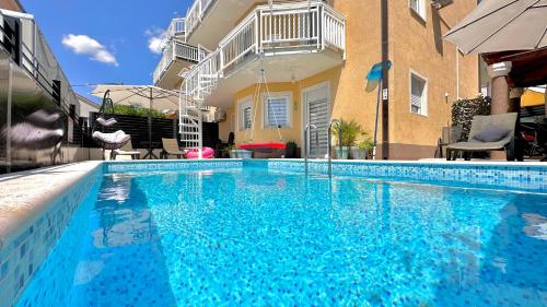 a large blue swimming pool in front of a building at Apartman Stipić 2 in Kaštela