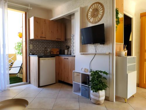 Il comprend une cuisine avec des placards en bois et une télévision murale. dans l'établissement 30m2 - Clim - wifi - 100m des plages, à Fréjus