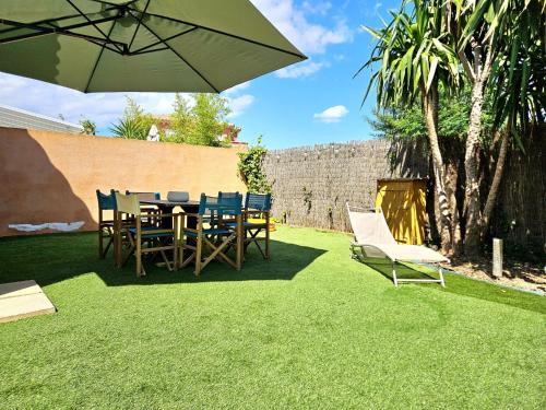 un patio avec une table, des chaises et un parasol dans l'établissement Les 4 Mas, à Bormes-les-Mimosas