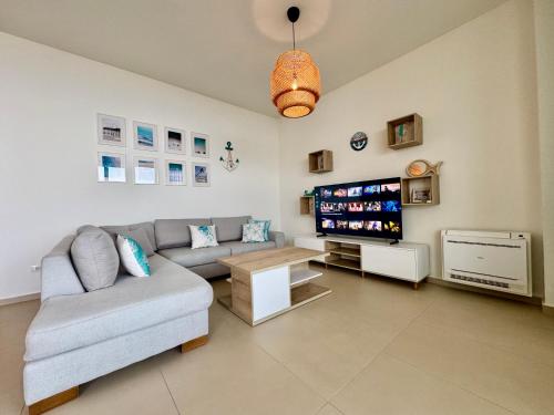 a living room with a couch and a tv at TIS, Green Coast in Palasë