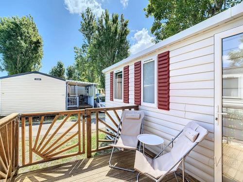 une terrasse avec deux chaises et une table dans l'établissement Mobil-Home CL 18 à Vias - La Carabasse - Camping Siblu avec piscine, à Vias