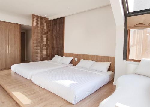 two beds in a room with white sheets at Meraki Villa Đà Lạt in Khu Chi Lăng