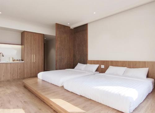 two beds in a bedroom with a large white bed at Meraki Villa Đà Lạt in Khu Chi Lăng