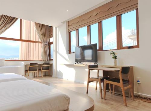 a hotel room with a bed and a desk with a television at Meraki Villa Đà Lạt in Khu Chi Lăng