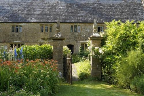 an old stone house with a gate in a garden at Lower Severalls Farmhouse in Crewkerne