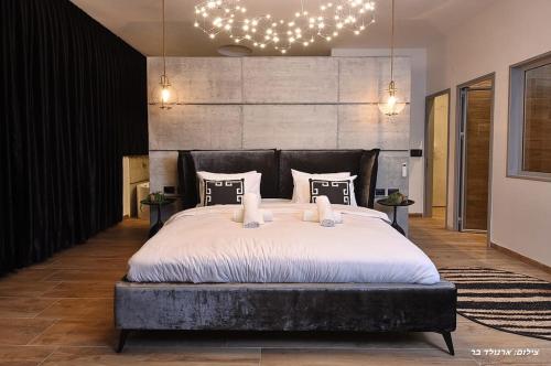 a bedroom with a large bed with white sheets and pillows at סוויטות בל - סוויטות יוקרה עם בריכה פרטית in Safed