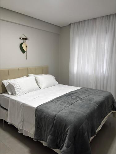 a white bedroom with a large bed with white curtains at Flat Diamond São Lourenço TOP 308 MG in São Lourenço