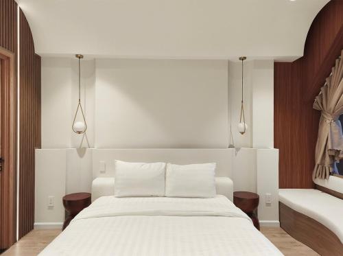 a bedroom with a large white bed with two lamps at Meraki Villa Đà Lạt in Khu Chi Lăng