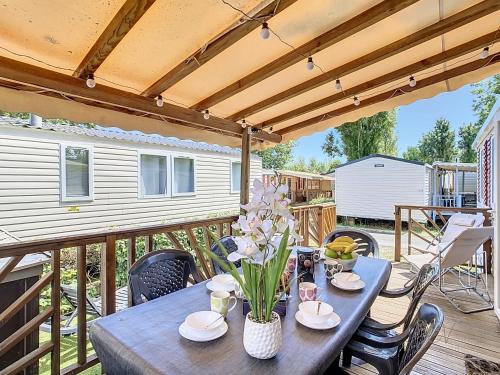 une table en bois avec des fleurs sur une terrasse dans l'établissement Mobil-Home CL 18 à Vias - La Carabasse - Camping Siblu avec piscine, à Vias