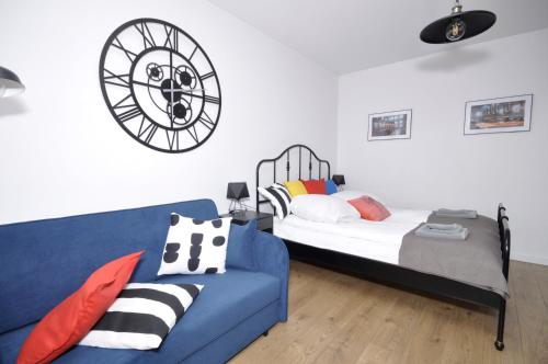 a bedroom with a blue couch and a clock on the wall at Schindler’s Factory Zabłocie Deluxe Apartments WAWELOFTS in Kraków