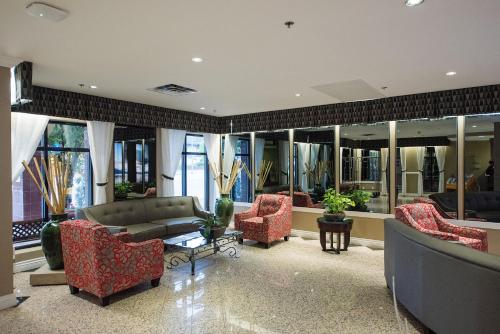 a living room with a couch and chairs and windows at Harrison Lake Hotel in Harrison Hot Springs