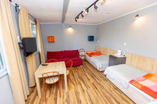 a room with two beds and a red couch at Gościniec Pod Markizami in Malbork