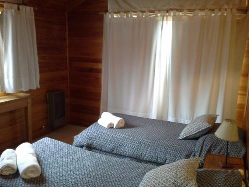 a bedroom with two beds and a window with towels at Las Cuatro Estaciones in San Martín de los Andes