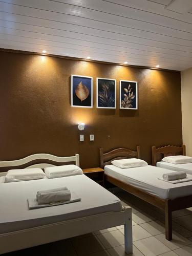 a room with two beds and two pictures on the wall at Chalé em Parque Aquático - Presidente Figueiredo in Presidente Figueiredo