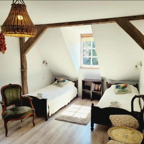 a attic room with two beds and a chair at Agroturystyka Rawiczówka in Brzeżno