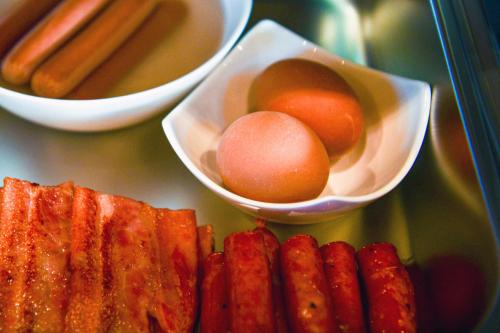 a plate of food with bacon and eggs and sausages at Pansion Villa Cancar in Grabovac