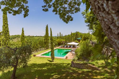 a pool in a garden with trees and a house at PODERE BAIOCCO TENUTA in Città della Pieve