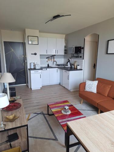 un salon avec un canapé et une cuisine dans l'établissement Mer et sable, à Cabourg