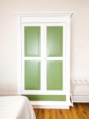 a white cabinet with green doors in a bedroom at Hotel Donatella in Posada