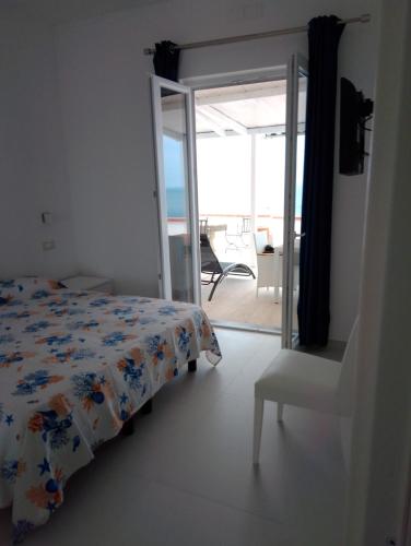 a bedroom with a bed and a chair and a balcony at Riflessi della baia in Ischia