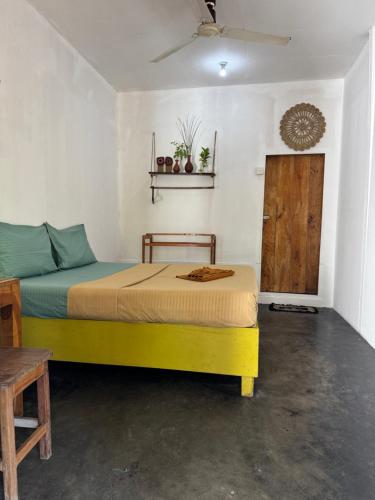 a bedroom with a yellow bed and a wooden door at Wave Hunters in Arugam Bay