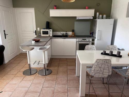 - une cuisine avec des appareils blancs, une table et des chaises dans l'établissement Villa Mela-Bella, à Ouistreham