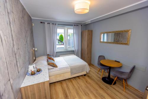 a bedroom with a bed and a table and a window at Gościniec Pod Markizami in Malbork