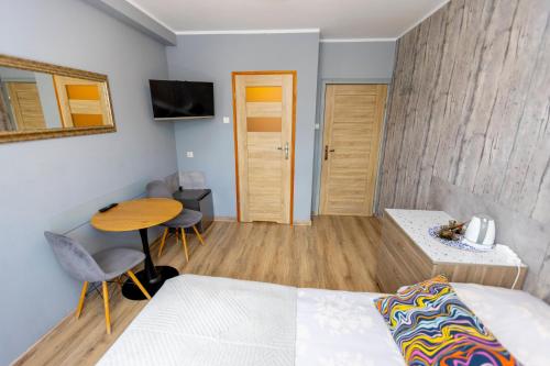 a bedroom with a bed and a table and a desk at Gościniec Pod Markizami in Malbork