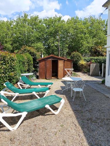 un groupe de chaises longues et une table et des chaises dans l'établissement Embrun - T2 avec jardin près de la Plage, à Saint-Nazaire