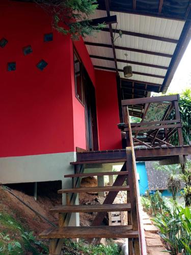 a red building with stairs leading to a door at Flor da Serra Chalés in Nova Friburgo